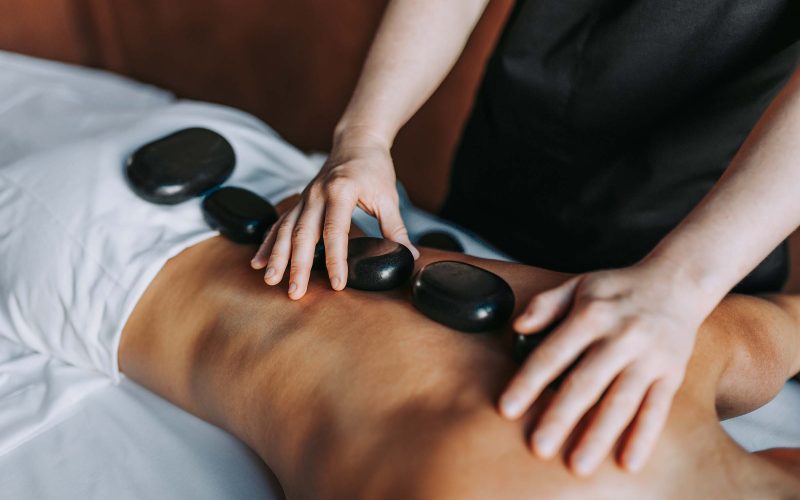 Person receiving a hot stone massage on their back.